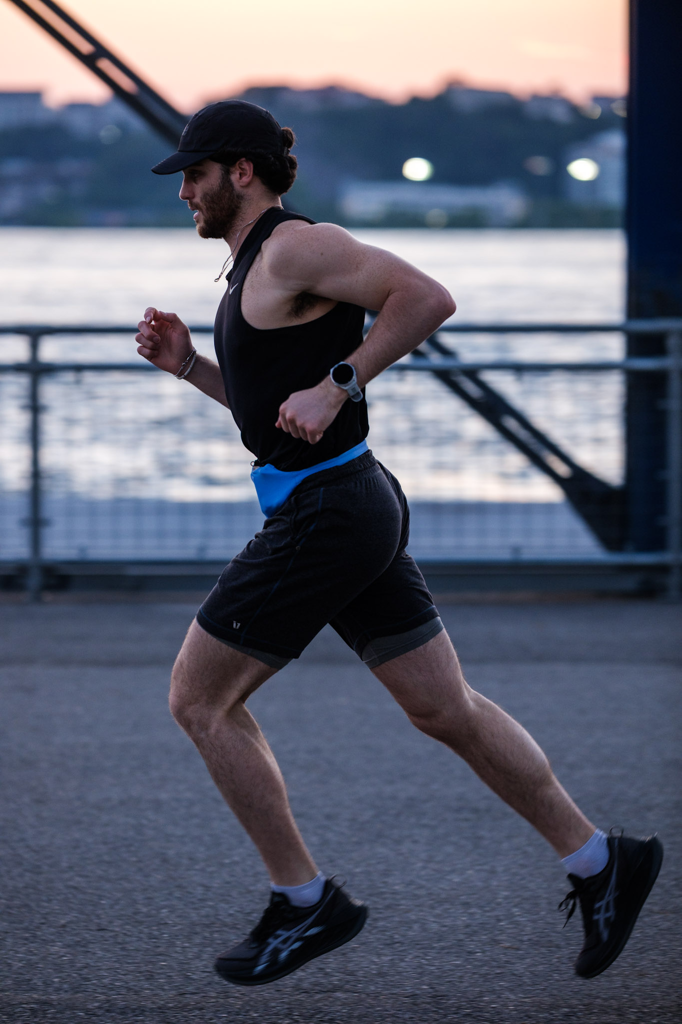 Runner mid-stride wearing the blue SwapBelt at the waterfront during twilight