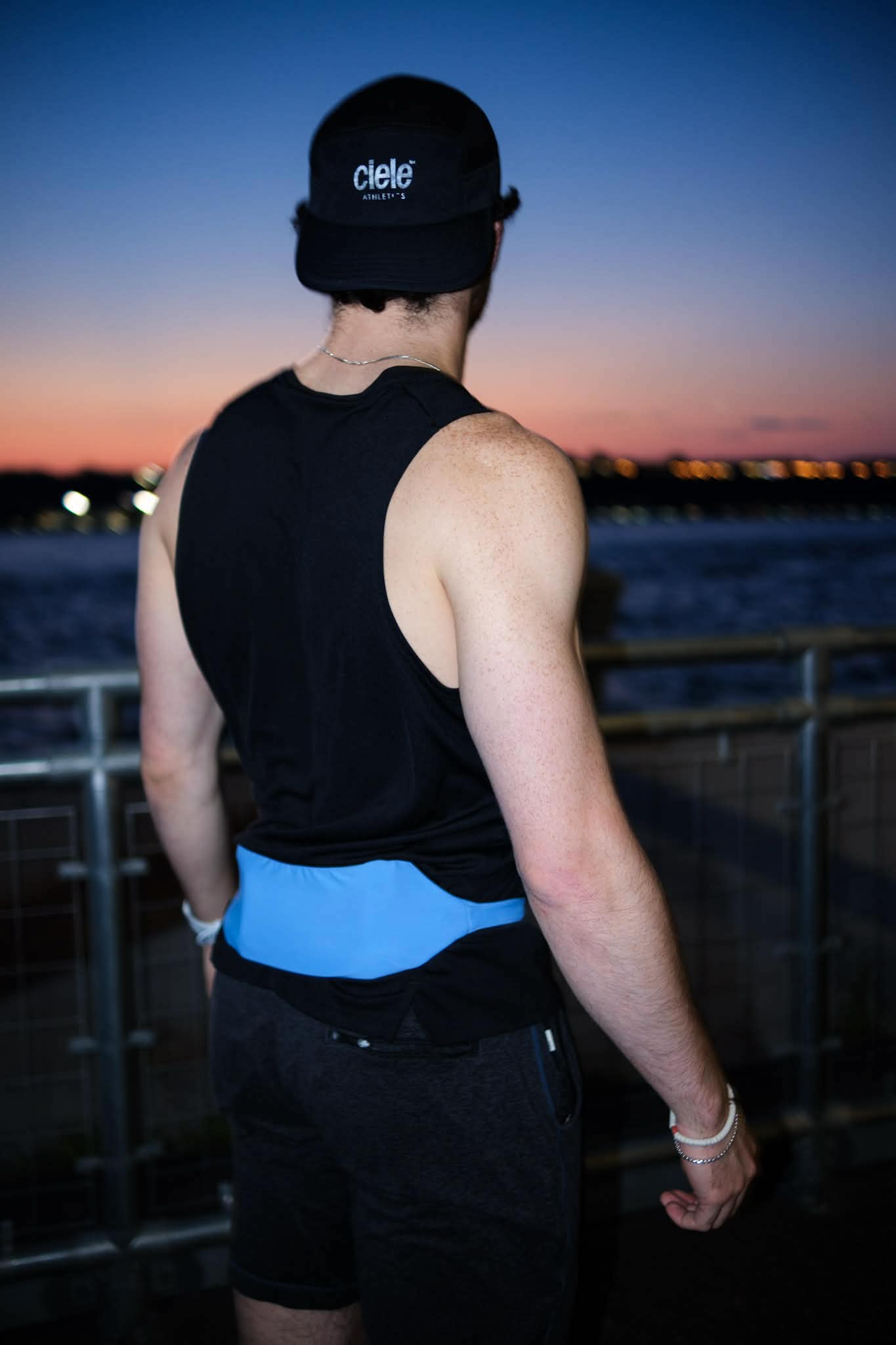 Runner wearing the blue SwapBelt looking out over the water at the city skyline during twilight